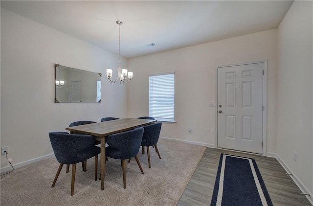 dining space featuring wood-type flooring and an inviting chandelier