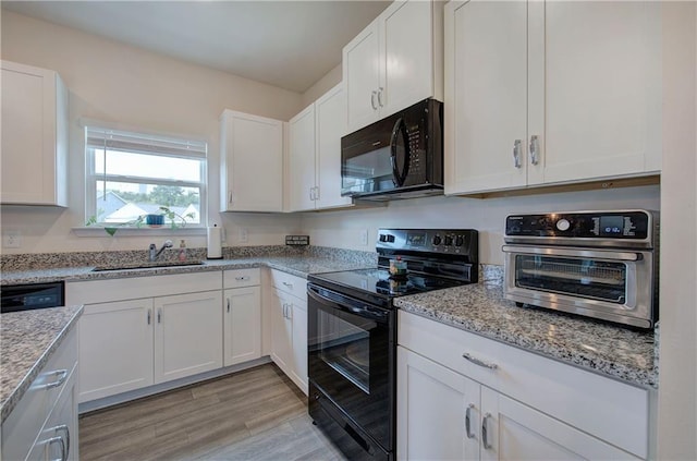 kitchen featuring sink, black appliances, light hardwood / wood-style flooring, light stone countertops, and white cabinets