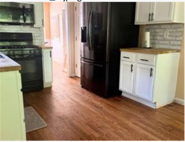 kitchen with white cabinets, light hardwood / wood-style flooring, and black appliances