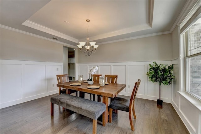 dining room with dark wood-style floors, a decorative wall, and a tray ceiling