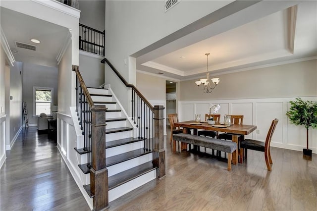 dining room with a tray ceiling, wood finished floors, and visible vents