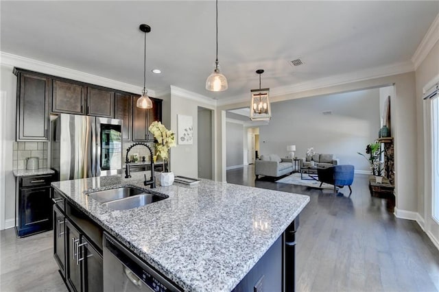 kitchen featuring ornamental molding, light wood-style flooring, a sink, backsplash, and stainless steel appliances