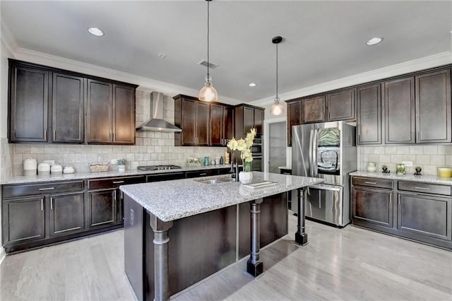 kitchen with crown molding, wall chimney exhaust hood, appliances with stainless steel finishes, and a sink