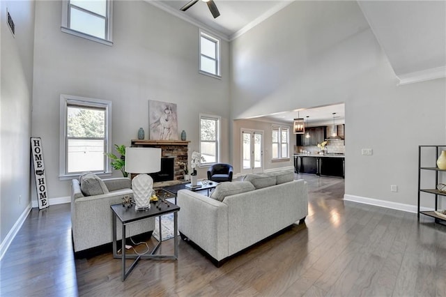 living room with baseboards, a fireplace, dark wood-style flooring, and crown molding