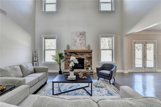 living room featuring a fireplace, baseboards, a towering ceiling, and wood finished floors