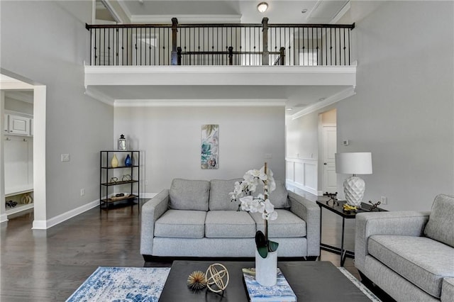 living room with baseboards, wood finished floors, a towering ceiling, and crown molding