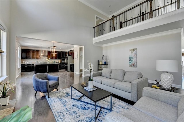 living area featuring crown molding, baseboards, light wood-type flooring, and a towering ceiling