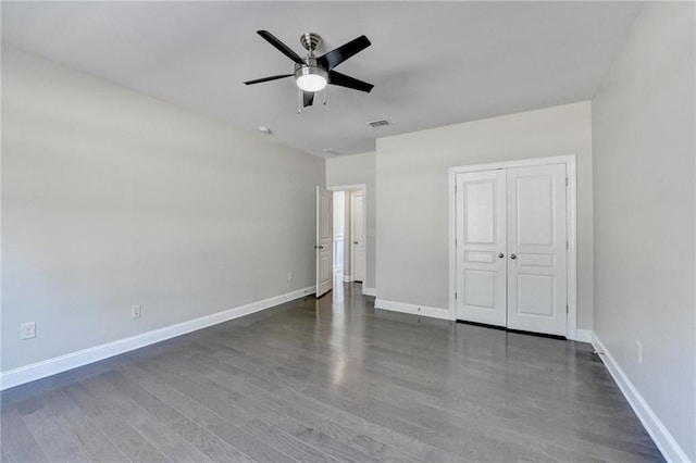 unfurnished bedroom featuring a ceiling fan, visible vents, wood finished floors, baseboards, and a closet