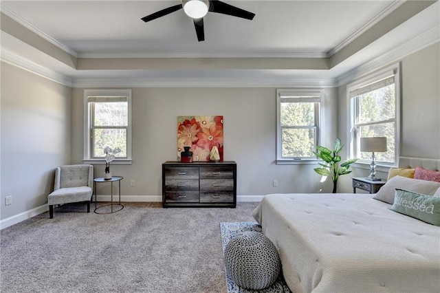 carpeted bedroom featuring ceiling fan, a tray ceiling, baseboards, and ornamental molding