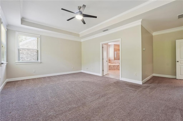 empty room with visible vents, a raised ceiling, ornamental molding, carpet flooring, and baseboards