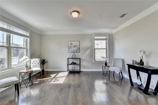 living area with visible vents, baseboards, wood finished floors, and crown molding