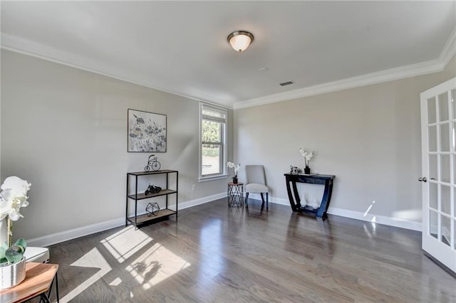 living area featuring baseboards, wood finished floors, visible vents, and ornamental molding