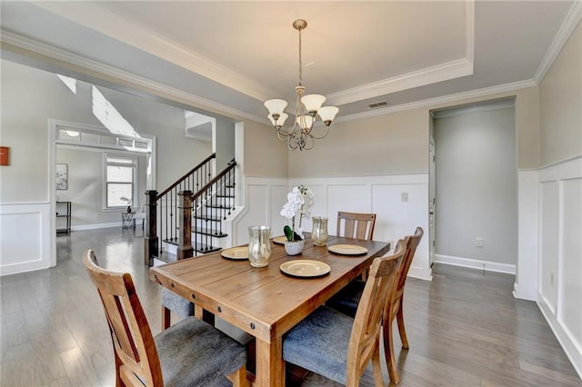 dining space with wood finished floors, visible vents, stairs, a raised ceiling, and a notable chandelier