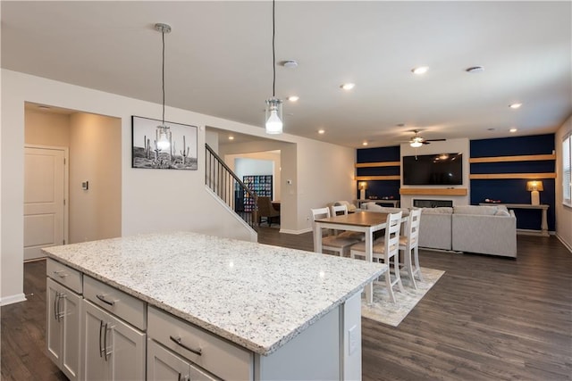 1076 Allspice Way, Lawrenceville, GA 30045 - kitchen featuring light stone counters, dark hardwood / wood-style floors, a center island, and hanging light fixtures