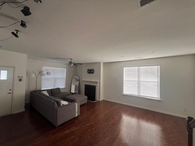 unfurnished living room featuring ceiling fan and dark wood-type flooring