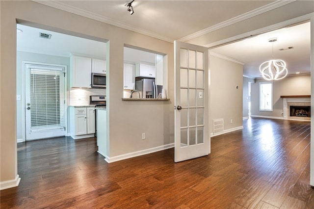 kitchen featuring white cabinets, a high end fireplace, appliances with stainless steel finishes, and dark wood-type flooring