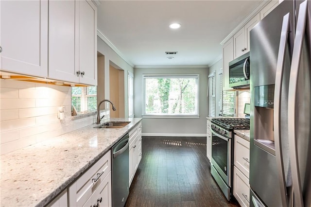 kitchen with tasteful backsplash, baseboards, appliances with stainless steel finishes, crown molding, and a sink