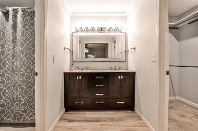 full bathroom featuring ornamental molding, a sink, baseboards, and double vanity