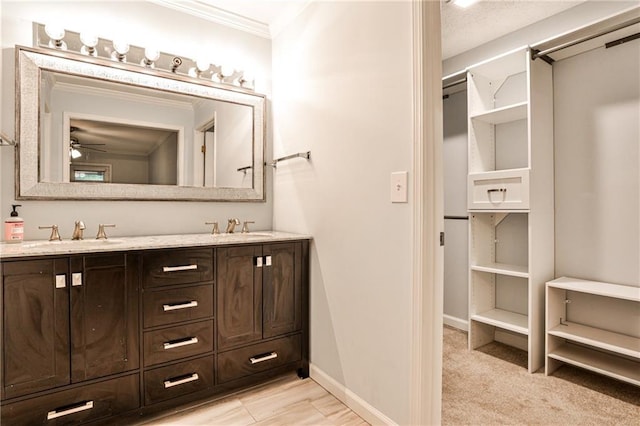 full bath with double vanity, baseboards, a sink, and ornamental molding