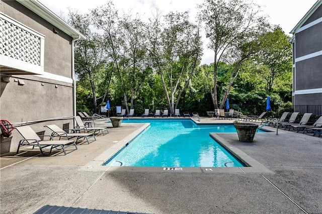 community pool with a patio area and fence