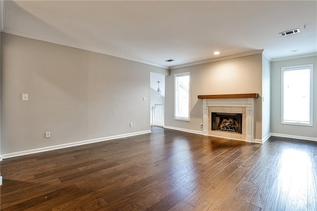 unfurnished living room with a tile fireplace, crown molding, dark hardwood / wood-style flooring, and plenty of natural light