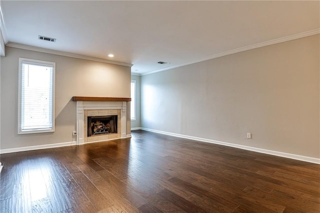 unfurnished living room with dark wood-style flooring, crown molding, visible vents, a tile fireplace, and baseboards