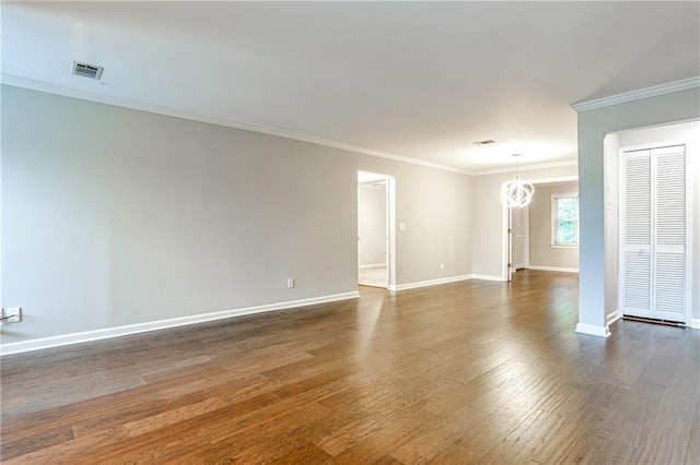 spare room with baseboards, visible vents, ornamental molding, dark wood-style flooring, and a chandelier