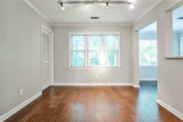 empty room featuring baseboards, wood finished floors, visible vents, and crown molding