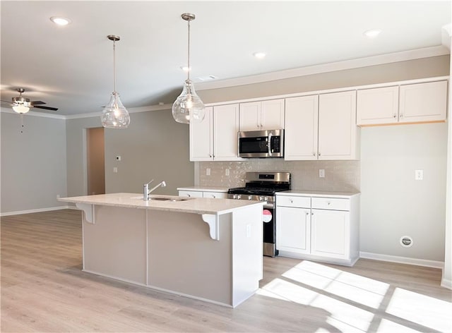 kitchen with sink, hanging light fixtures, a kitchen island with sink, white cabinets, and appliances with stainless steel finishes