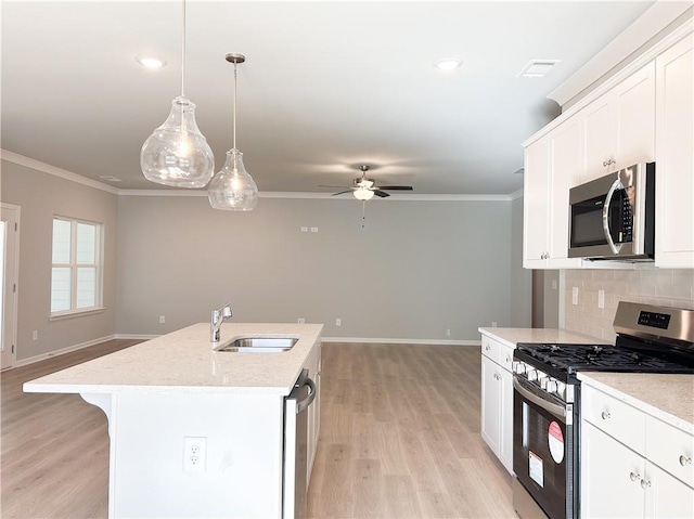 kitchen with a kitchen island with sink, decorative light fixtures, decorative backsplash, white cabinets, and appliances with stainless steel finishes