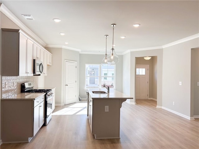 kitchen featuring stainless steel appliances, a center island with sink, light hardwood / wood-style floors, and sink