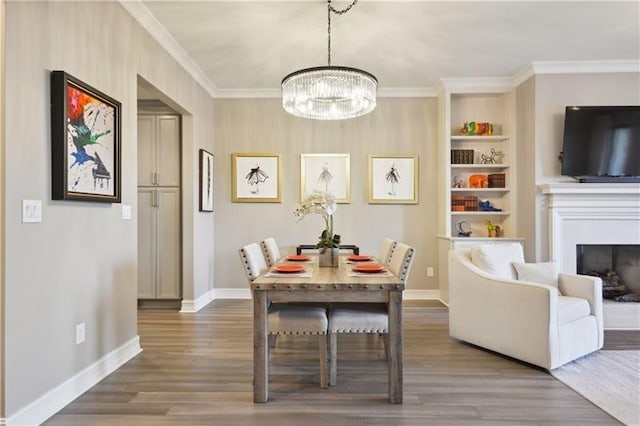 dining area featuring crown molding, an inviting chandelier, dark hardwood / wood-style flooring, and built in features