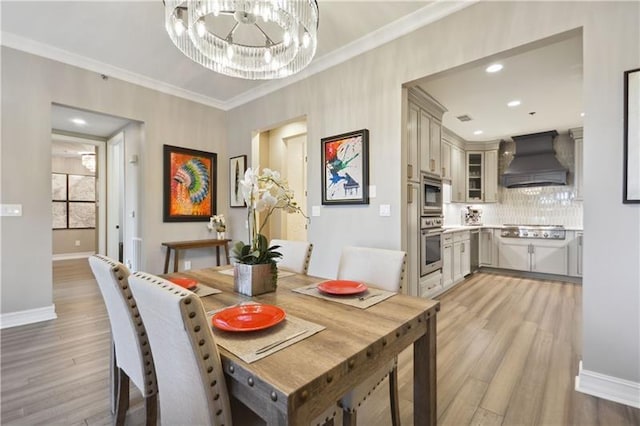 dining room featuring a notable chandelier, light hardwood / wood-style floors, and crown molding