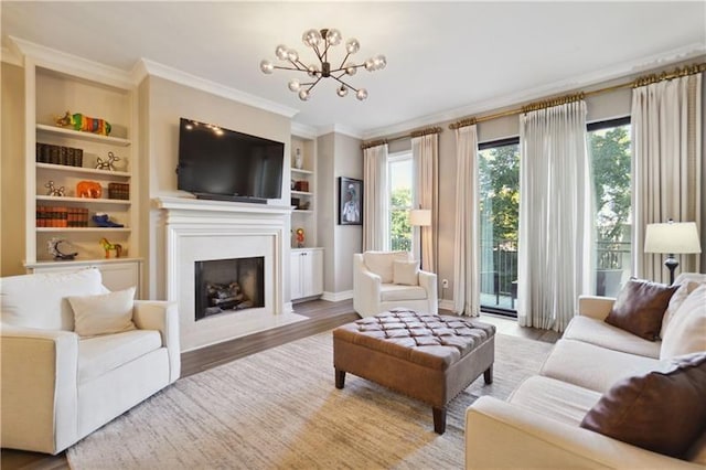 living room with built in features, ornamental molding, a chandelier, and wood-type flooring