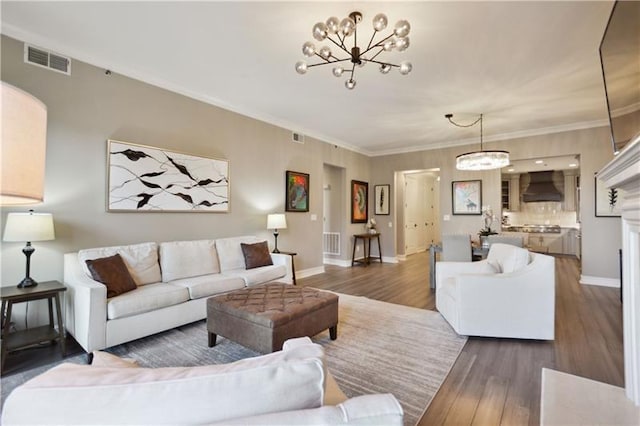 living room featuring a chandelier, dark wood-type flooring, and ornamental molding