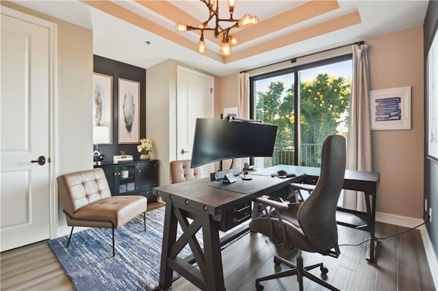 office space with dark wood-type flooring, an inviting chandelier, and a raised ceiling