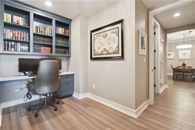 office space with built in desk and light hardwood / wood-style flooring