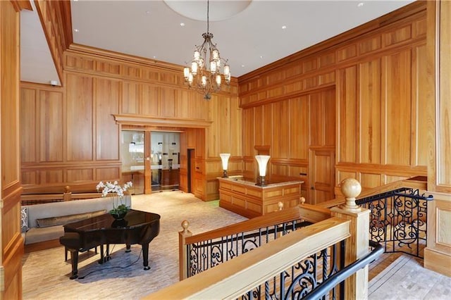 living area with a notable chandelier, ornamental molding, light carpet, and wooden walls