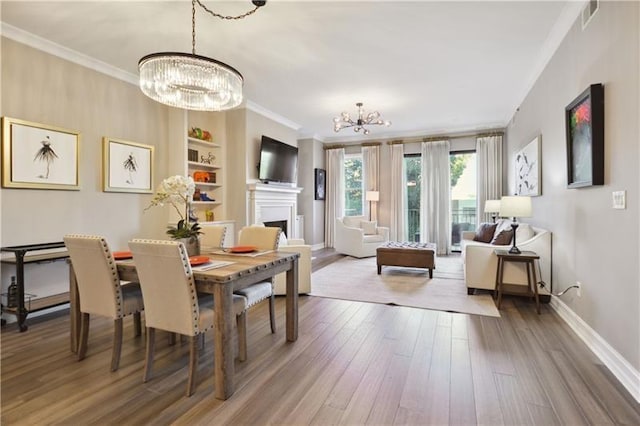 dining area with hardwood / wood-style flooring, ornamental molding, and an inviting chandelier