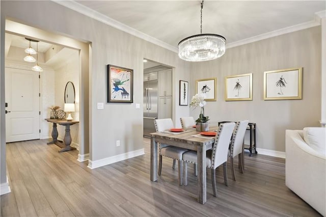 dining room with an inviting chandelier, hardwood / wood-style flooring, and ornamental molding