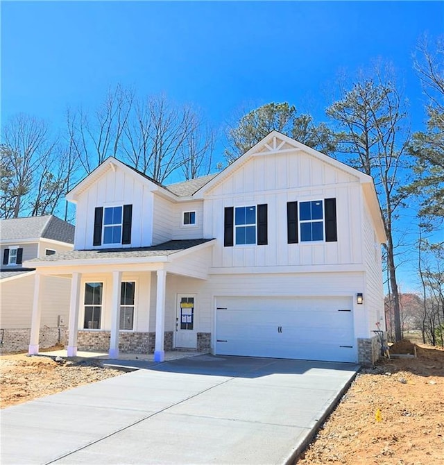 modern inspired farmhouse with driveway, a garage, stone siding, covered porch, and board and batten siding