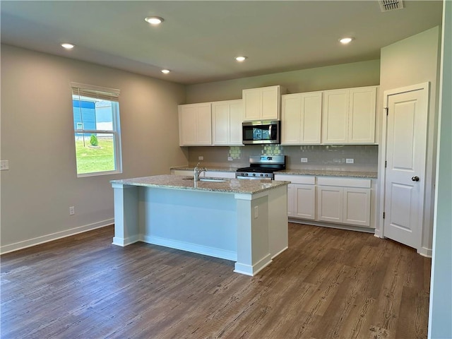 kitchen with backsplash, appliances with stainless steel finishes, a kitchen island with sink, white cabinetry, and a sink