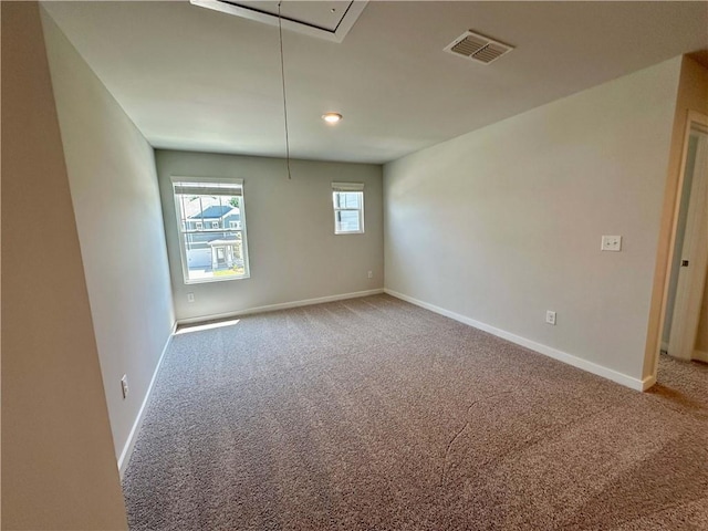 carpeted empty room featuring attic access, visible vents, and baseboards