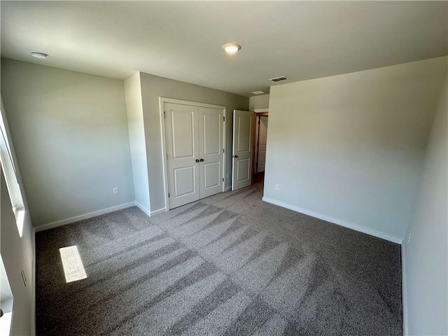 unfurnished bedroom with carpet floors, a closet, visible vents, and baseboards