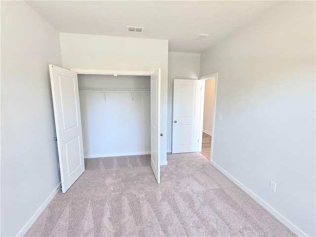 unfurnished bedroom featuring carpet floors, a closet, visible vents, and baseboards