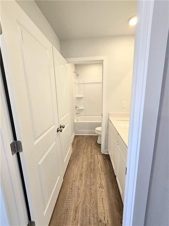 bathroom with toilet, bathtub / shower combination, wood finished floors, and vanity