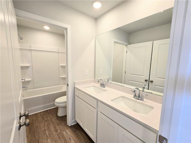 bathroom with double vanity, wood finished floors, a sink, and toilet