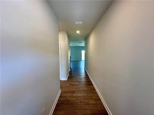 corridor with baseboards, visible vents, and dark wood-type flooring