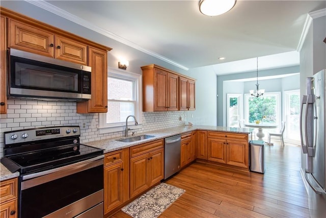 kitchen with sink, appliances with stainless steel finishes, light stone counters, ornamental molding, and light hardwood / wood-style floors