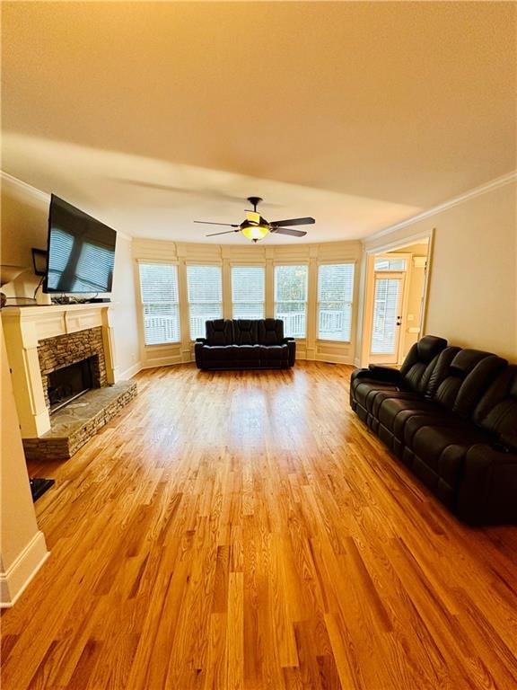 unfurnished living room with a fireplace, crown molding, light hardwood / wood-style flooring, and ceiling fan